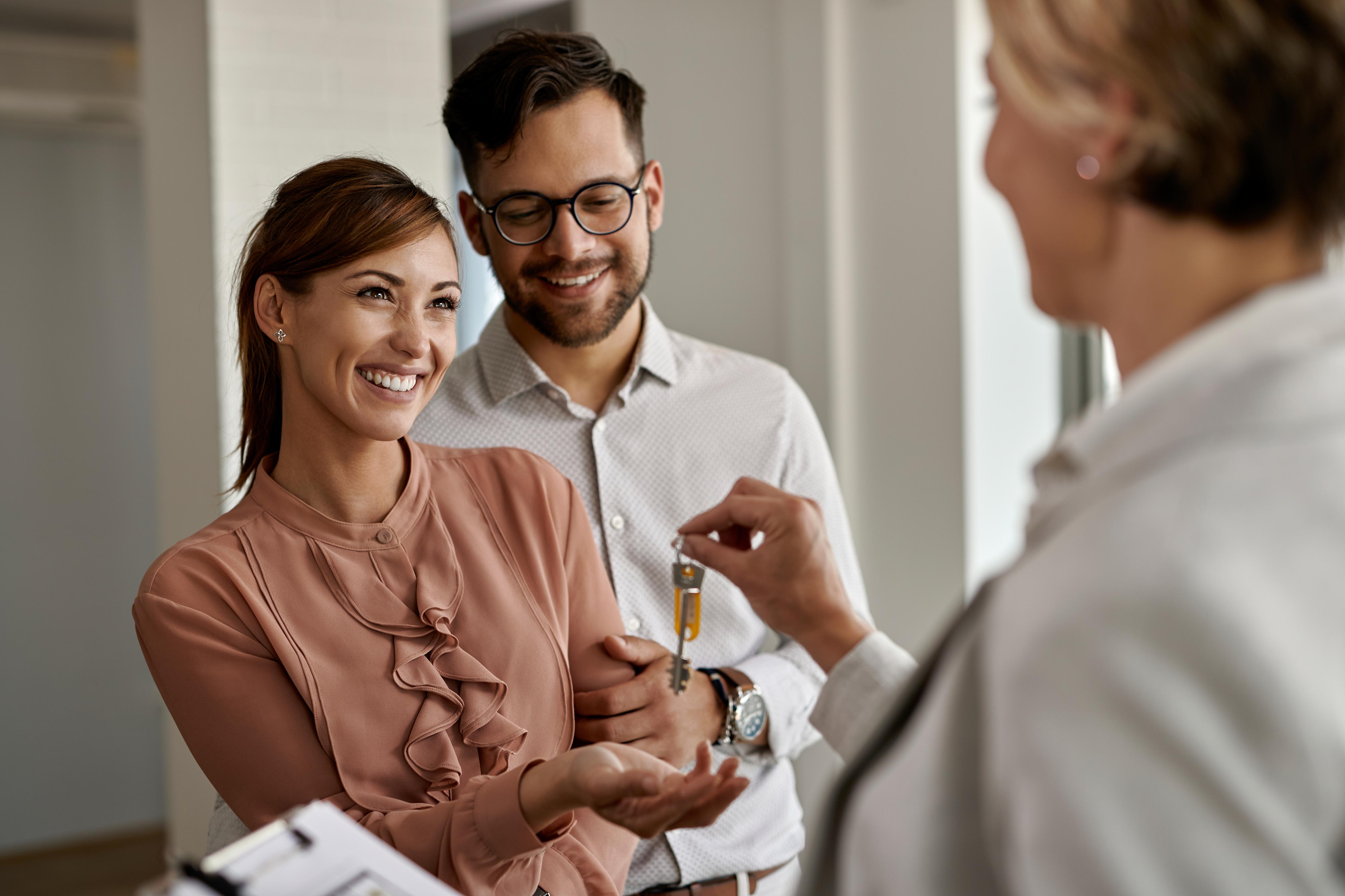 Family receiving house keys from an agent outside their new home