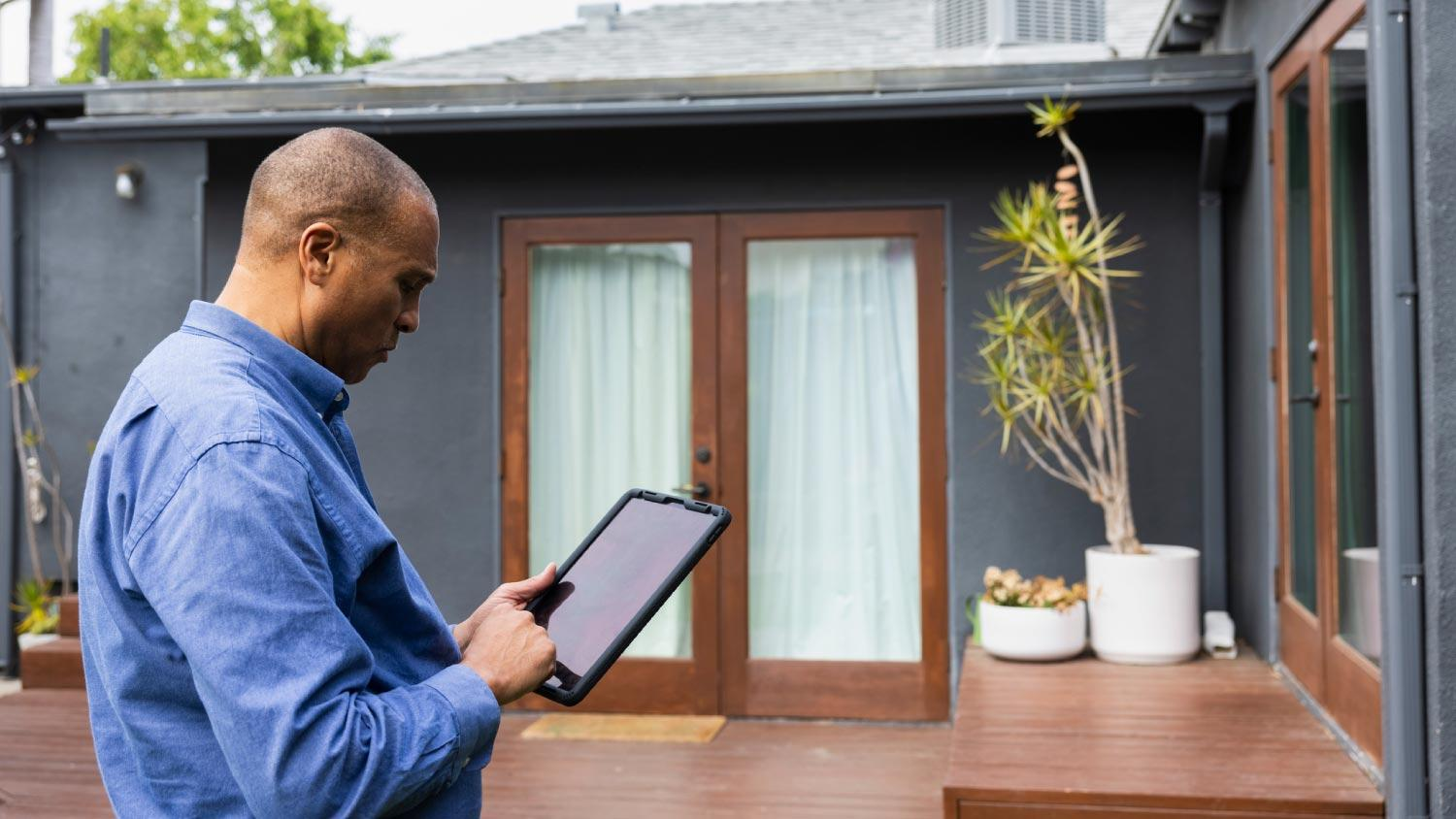 Agent assessing a home's value on a tablet outside the property