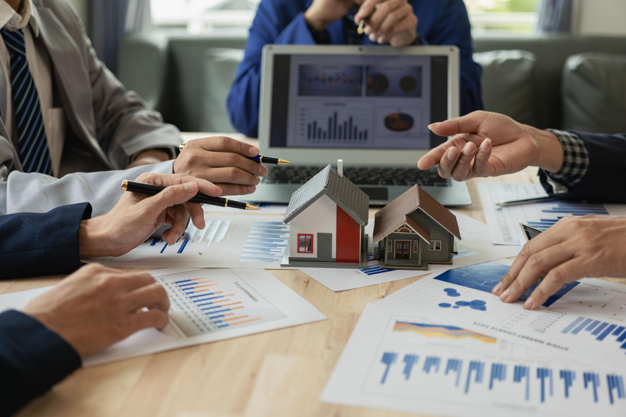 Investors reviewing property deals and market charts around a table