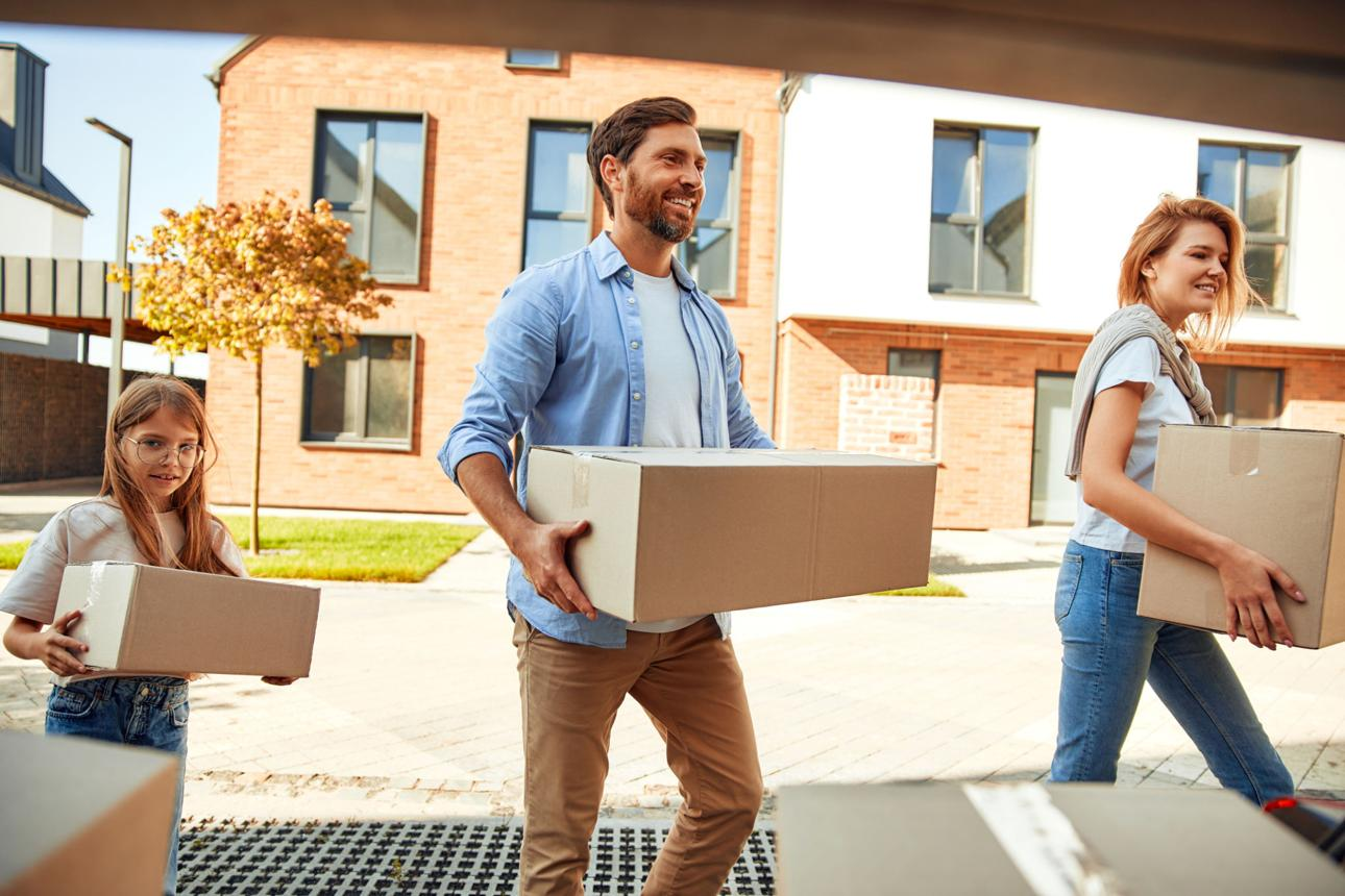 Family carrying moving boxes into their new home